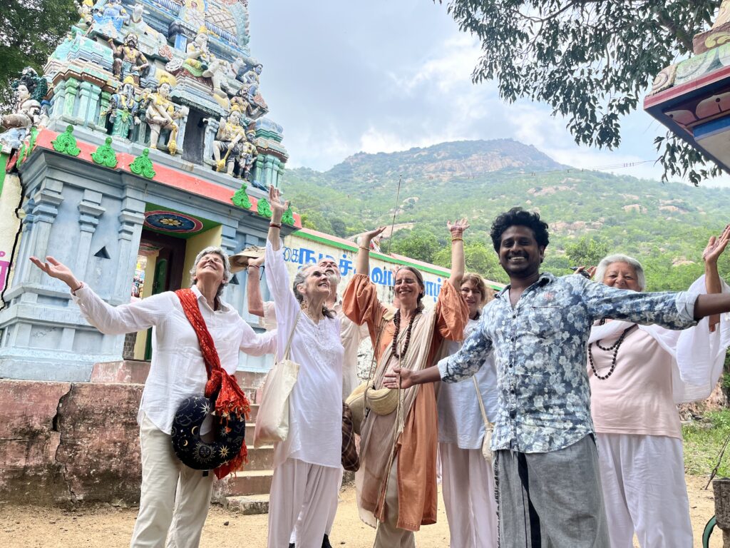 Group of friends joyfully posing near a temple with a mountain backdrop.