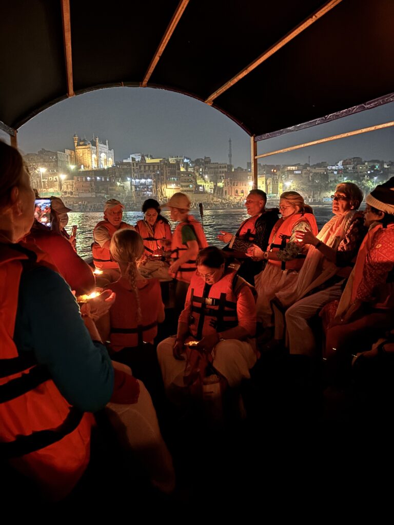 Group enjoying a cozy candlelit boat ride at night.
