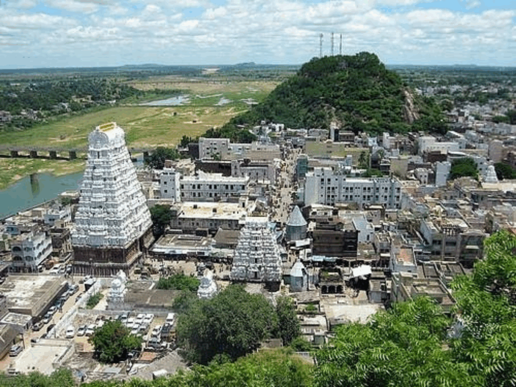 A historic temple complex with multiple gopurams set in a lush landscape.