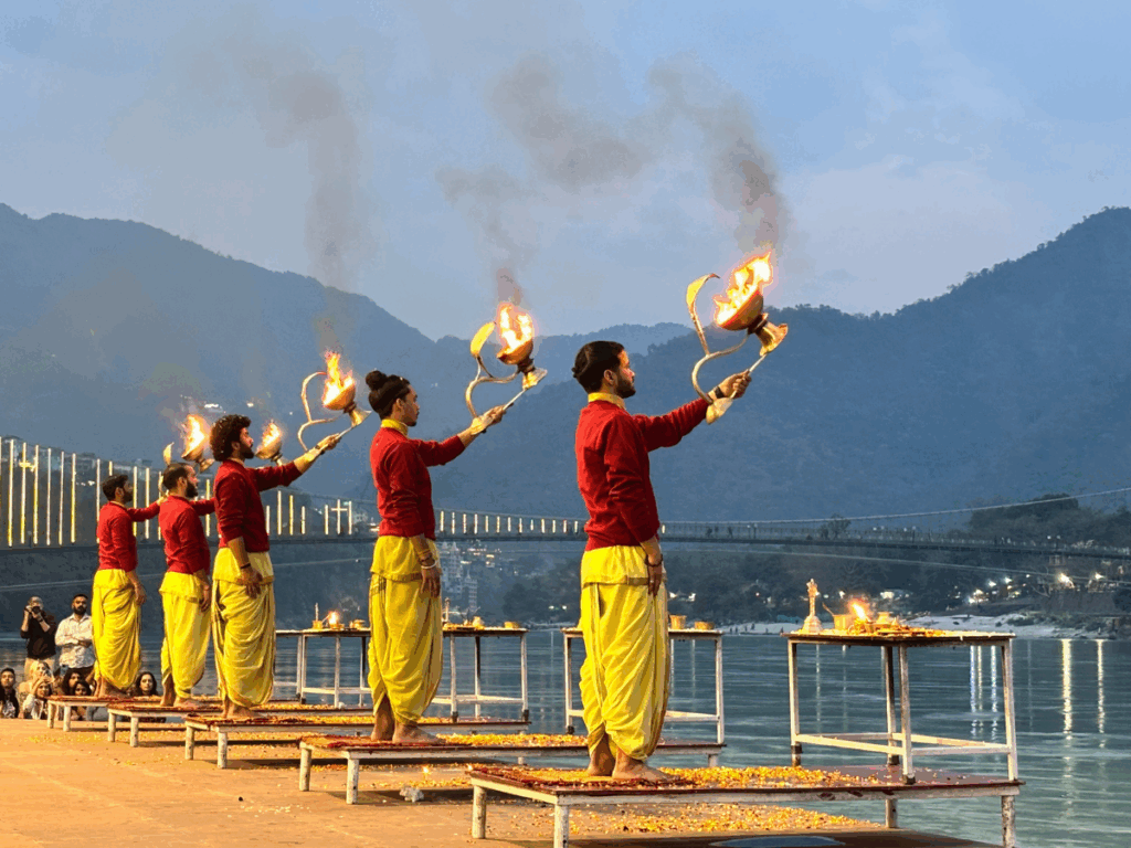 People performing a traditional fire ritual by the river at dusk.
